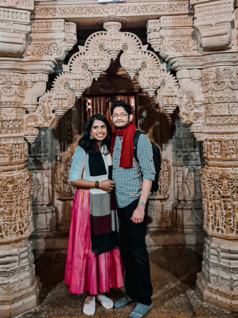Roopesh and Kiki from RooKiExplorers standing under an arch in a jain temple inside the Jaisalmer fort.