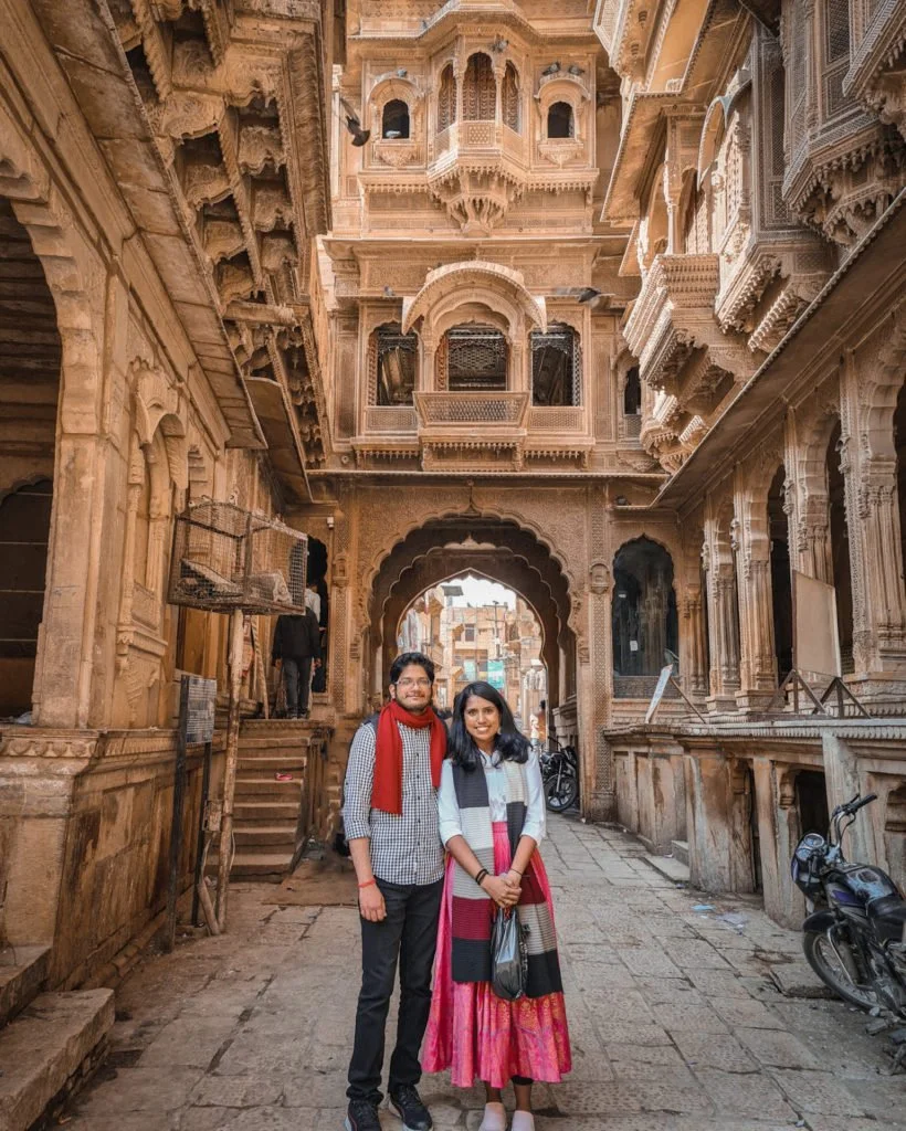 Roopesh and Kiki from RooKiExplorers standing in front of a traditional haveli in Jaisalmer.