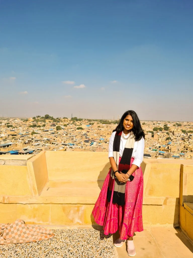 Kiki from RooKiExplorers standing in an old historic fort with the city of Jaisalmer as the backdrop.