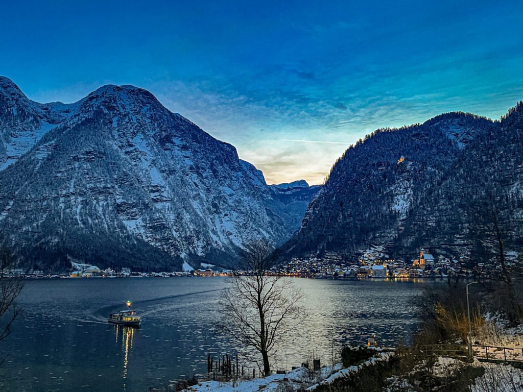 A ferry on a lake between the ferry station and Hallstatt at night.
