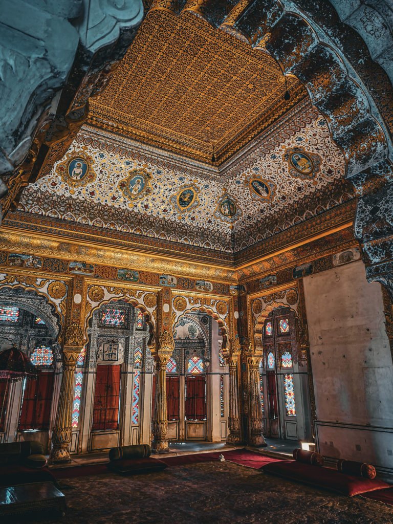 A room filled with paintings. The ceiling and pillars have gold on them.