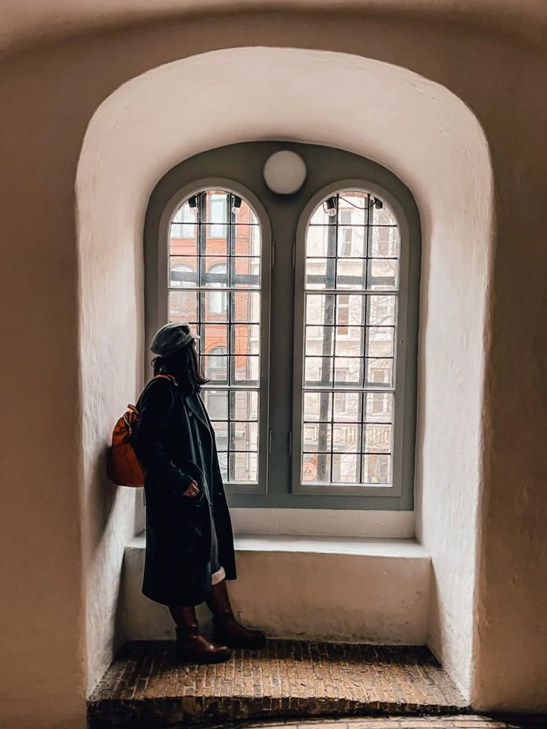 Kiki from RooKiExplorers looking outside a window in Round Tower, Copenhagen.