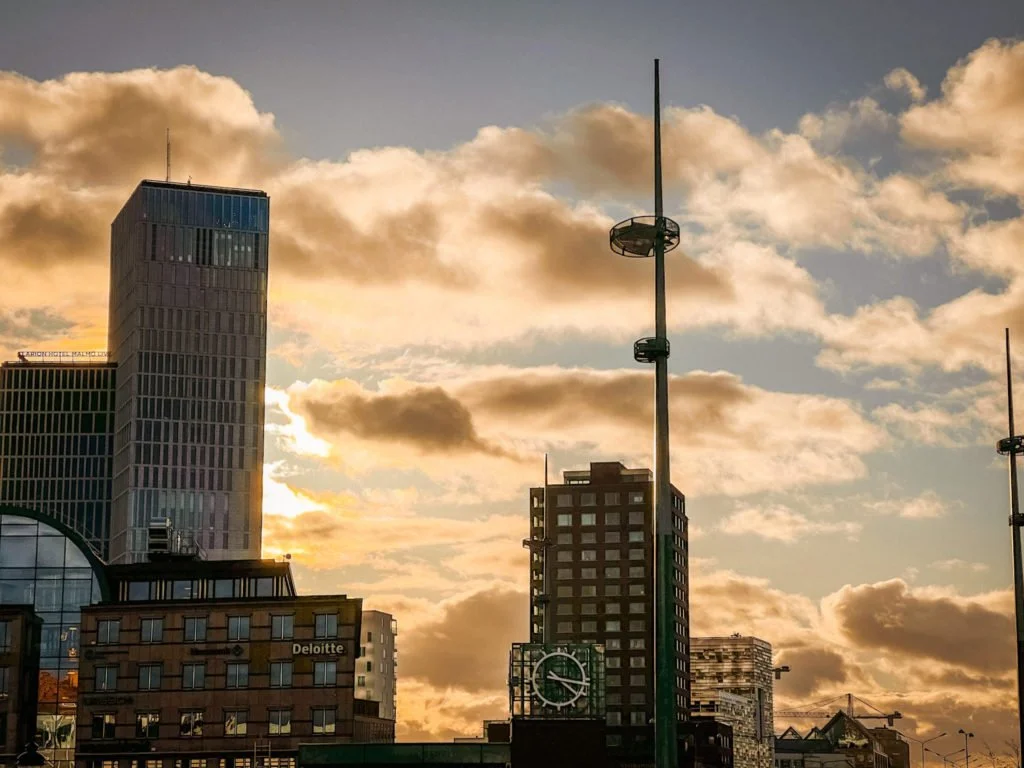 A few buildings in Malmo with the sun hiding behind one of the buildings.
