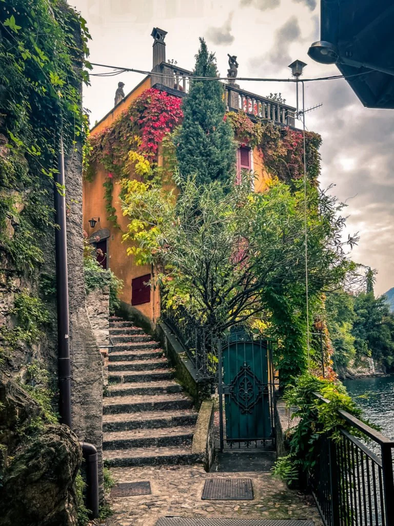 A yellow building covered with vines and other plants near the dock of Nesso.
