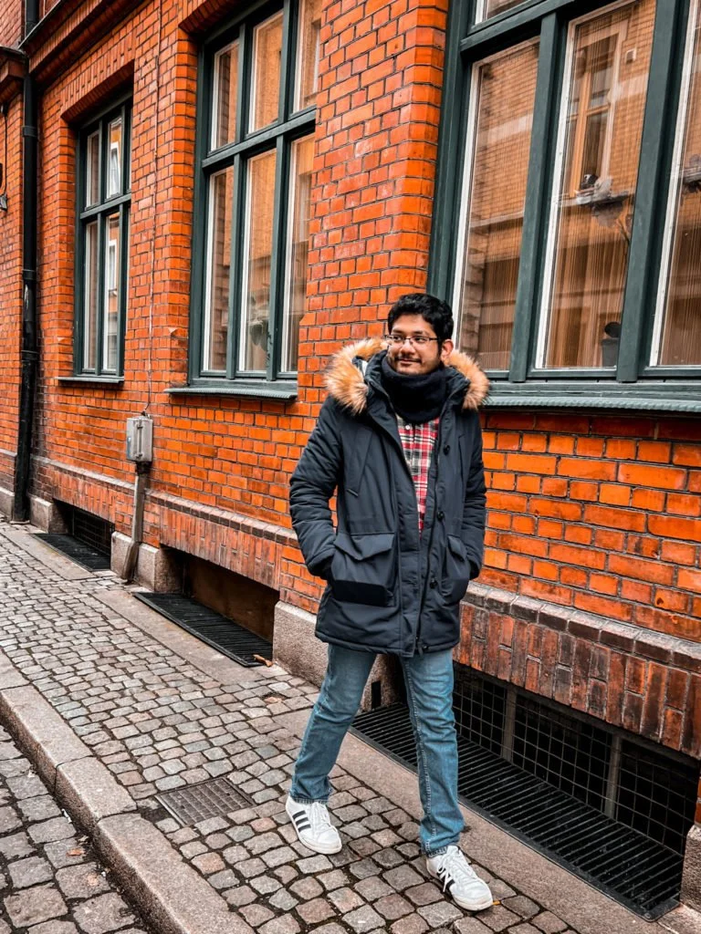 Roopesh from RooKiExplorers walking in front of a building in Lilla Torg.