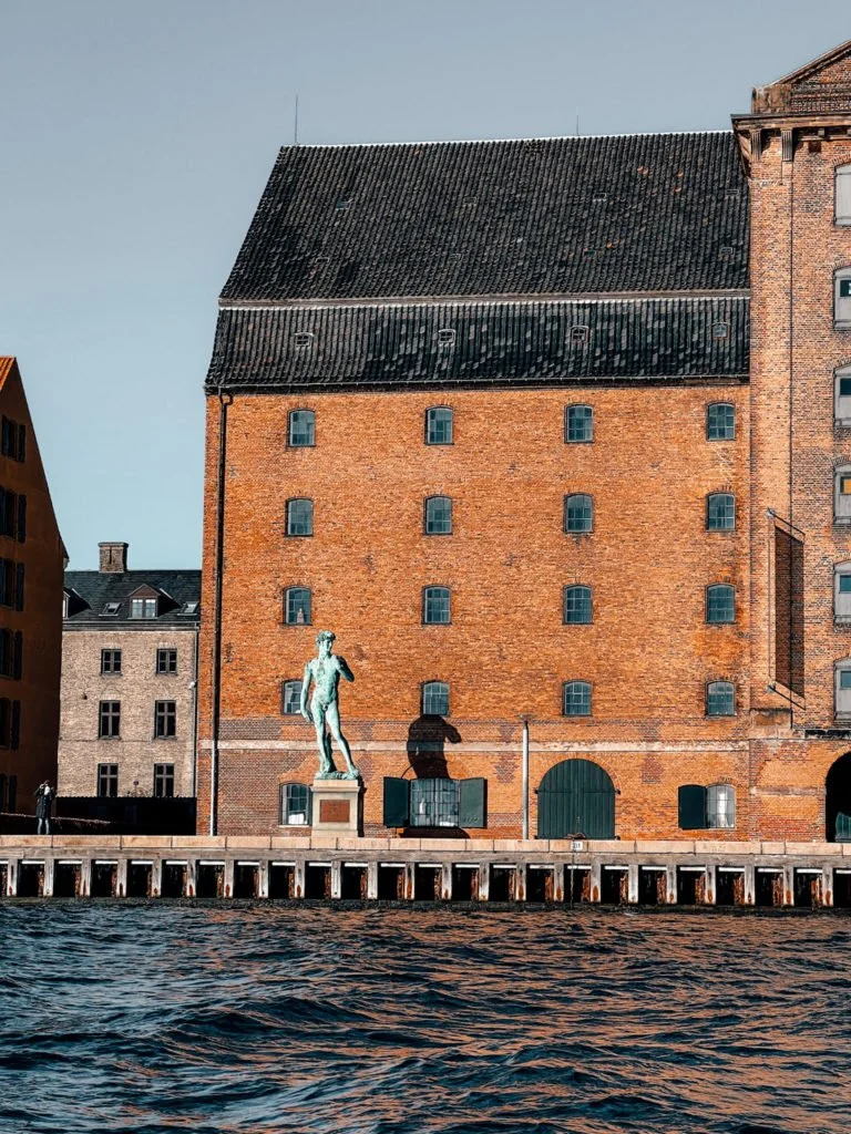A statue of a man near a building in Copenhagen's waterfront.