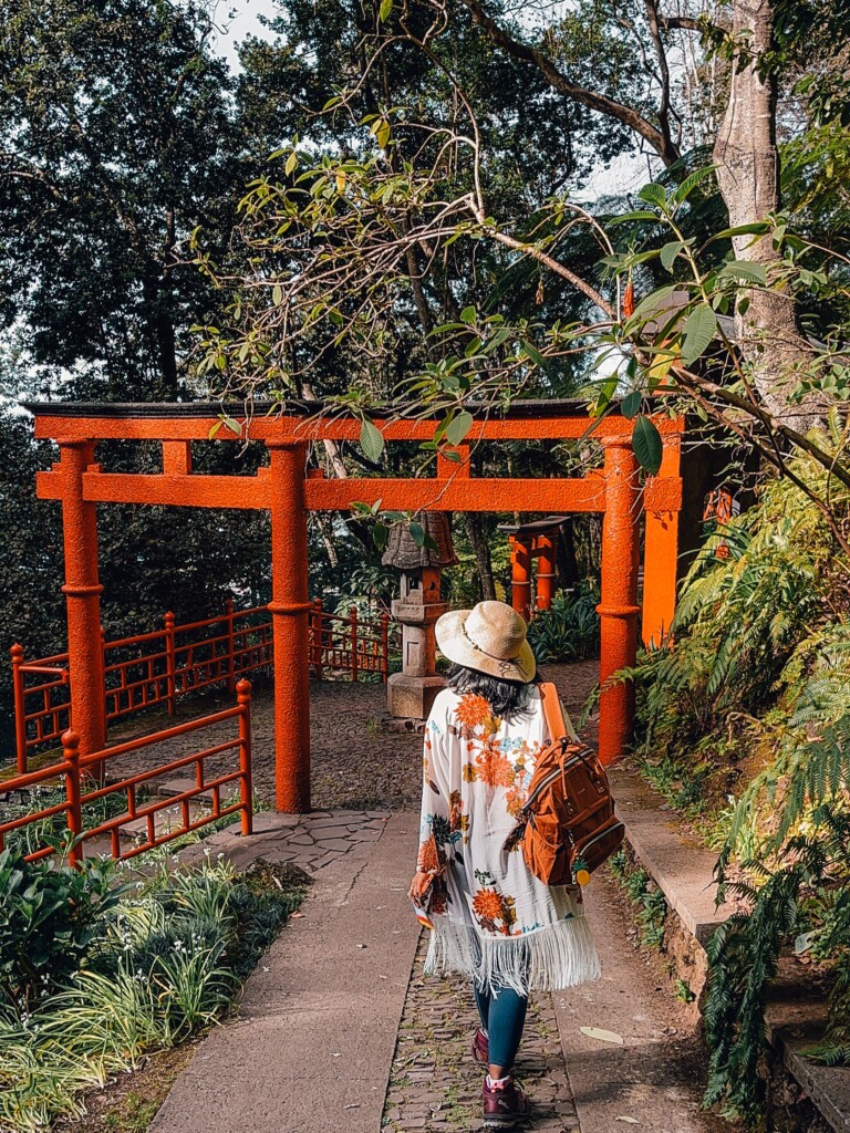 Kiki from RooKiExplorers strolling on a path filled with traditional Japanese arches in Monte Palace Garden in Funchal.