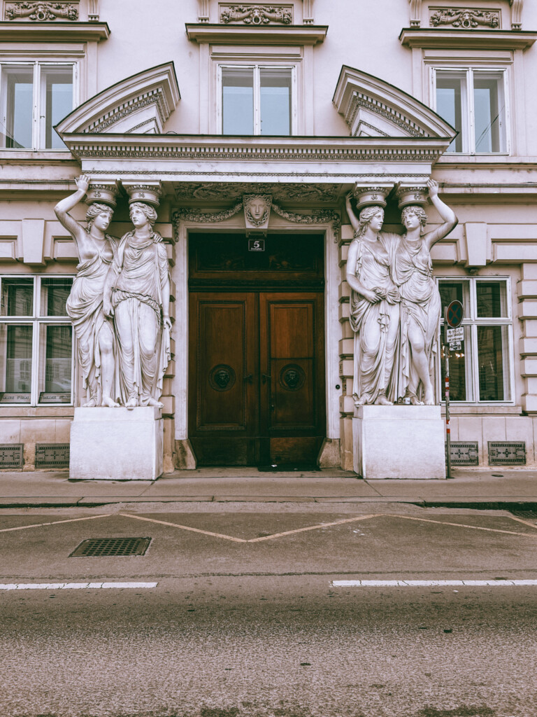 A random building with a beautiful wooden door with statues on either side in Vienna.