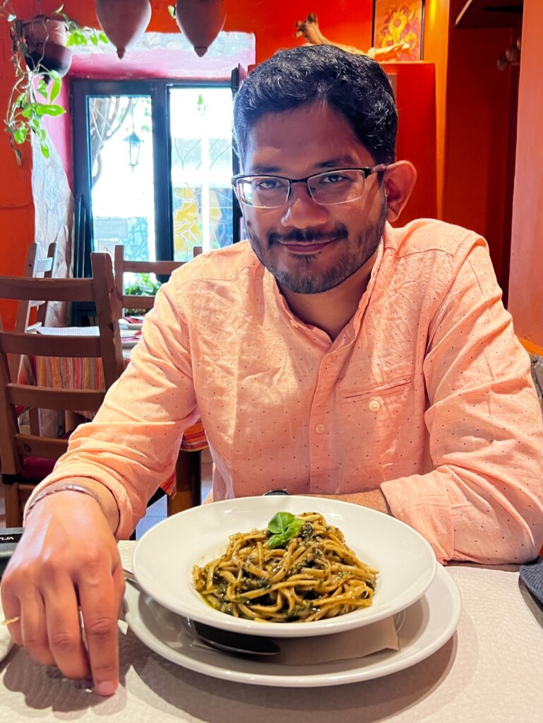 Roopesh from RooKiExplorers posing with a bowl of pasta in a restaurant in Ferragudo, Algarve.