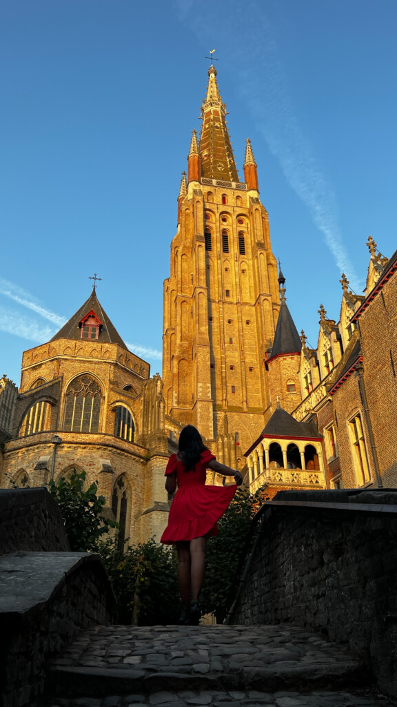 Kiki from RooKiExplorers posing in front of the Church of Our Lady in Bruges, Belgium.